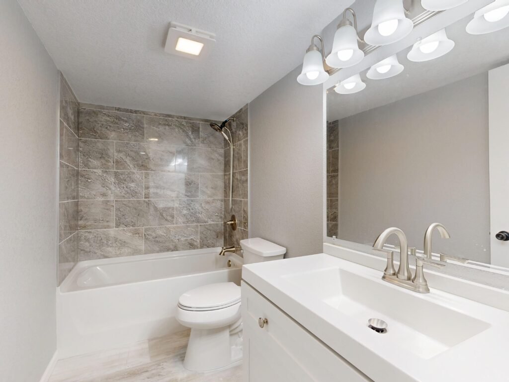Elegant modern bathroom featuring marble tiles and sleek white vanity.